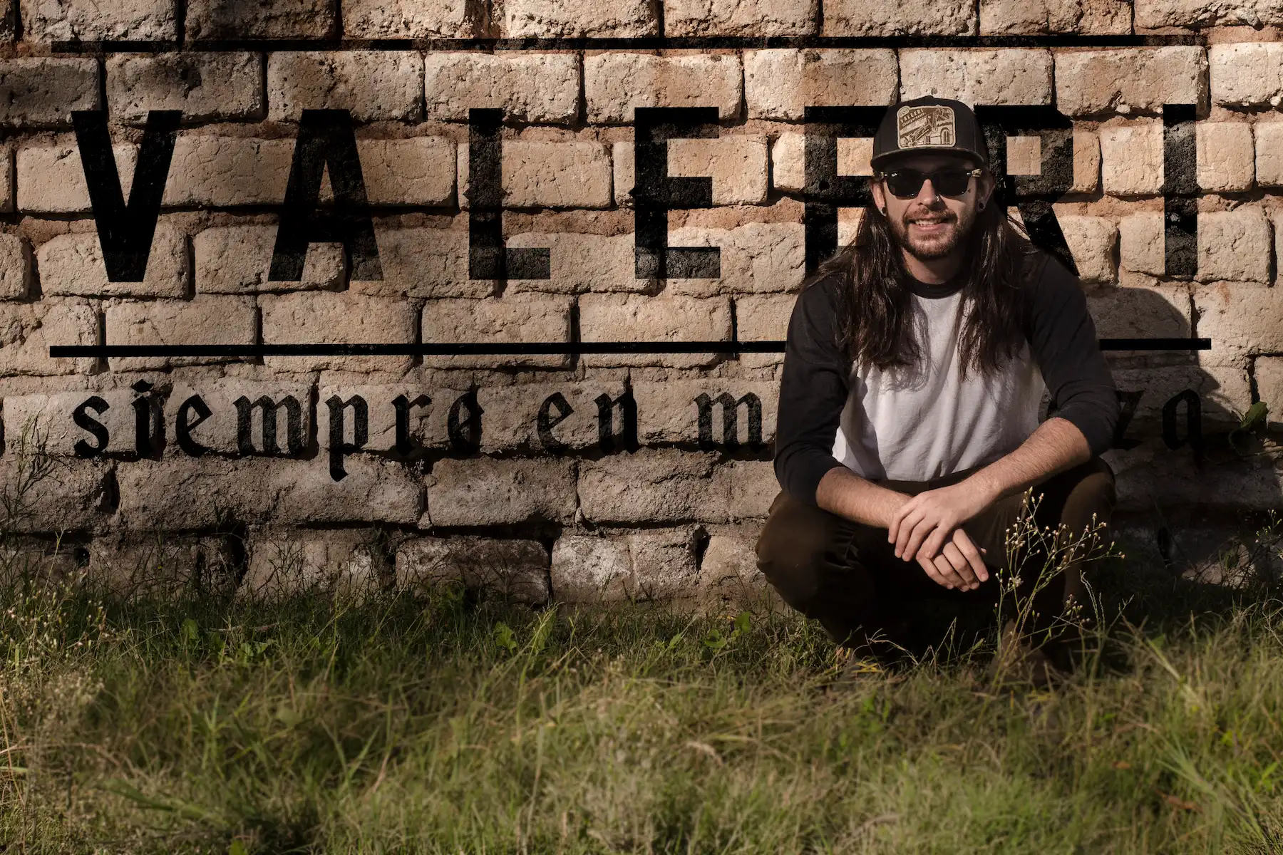 Chico usando gorra Valeeri posando frente un muro con el logo de la empresa