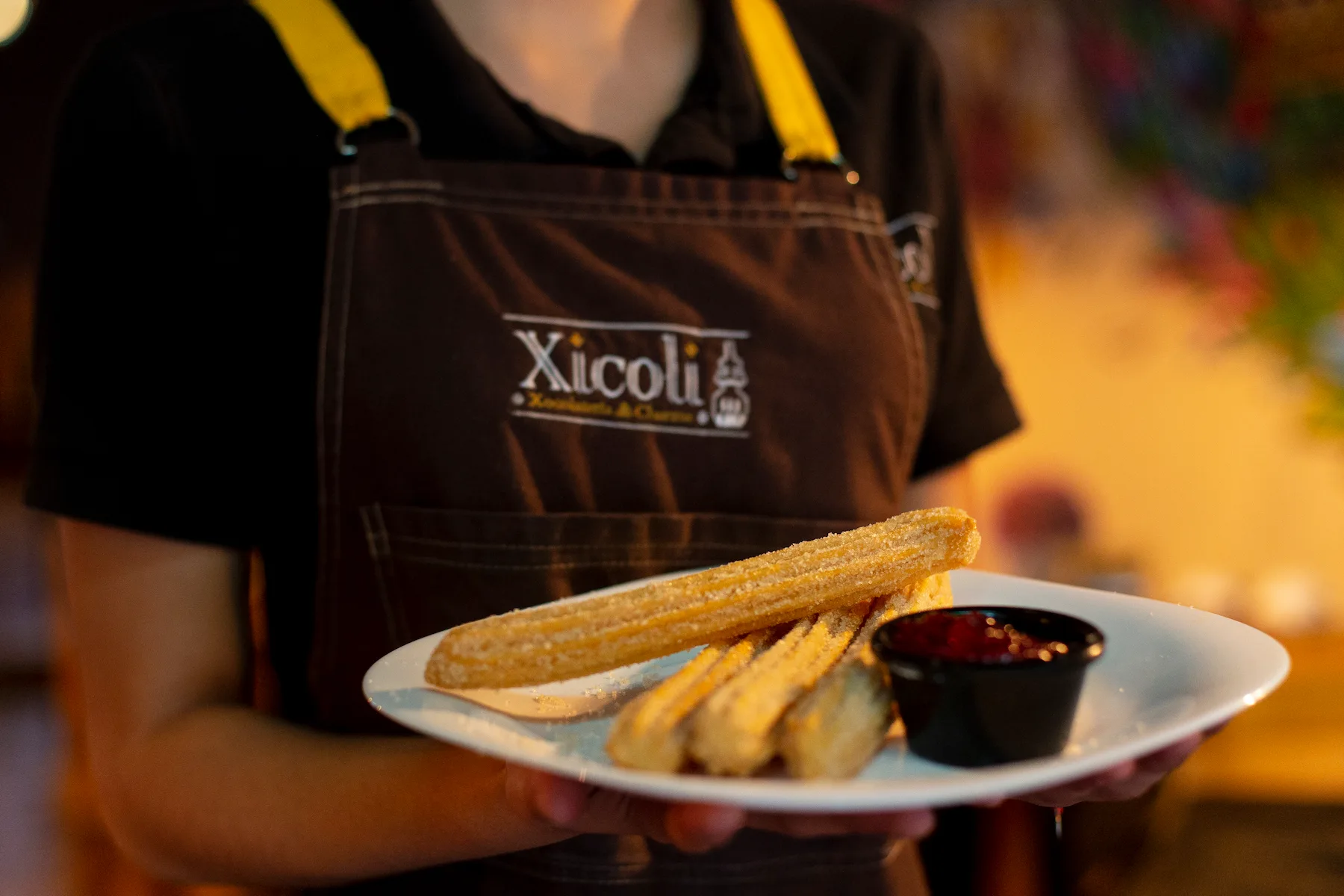 Trabajadora de Xicoli con un plato con churros de azucar