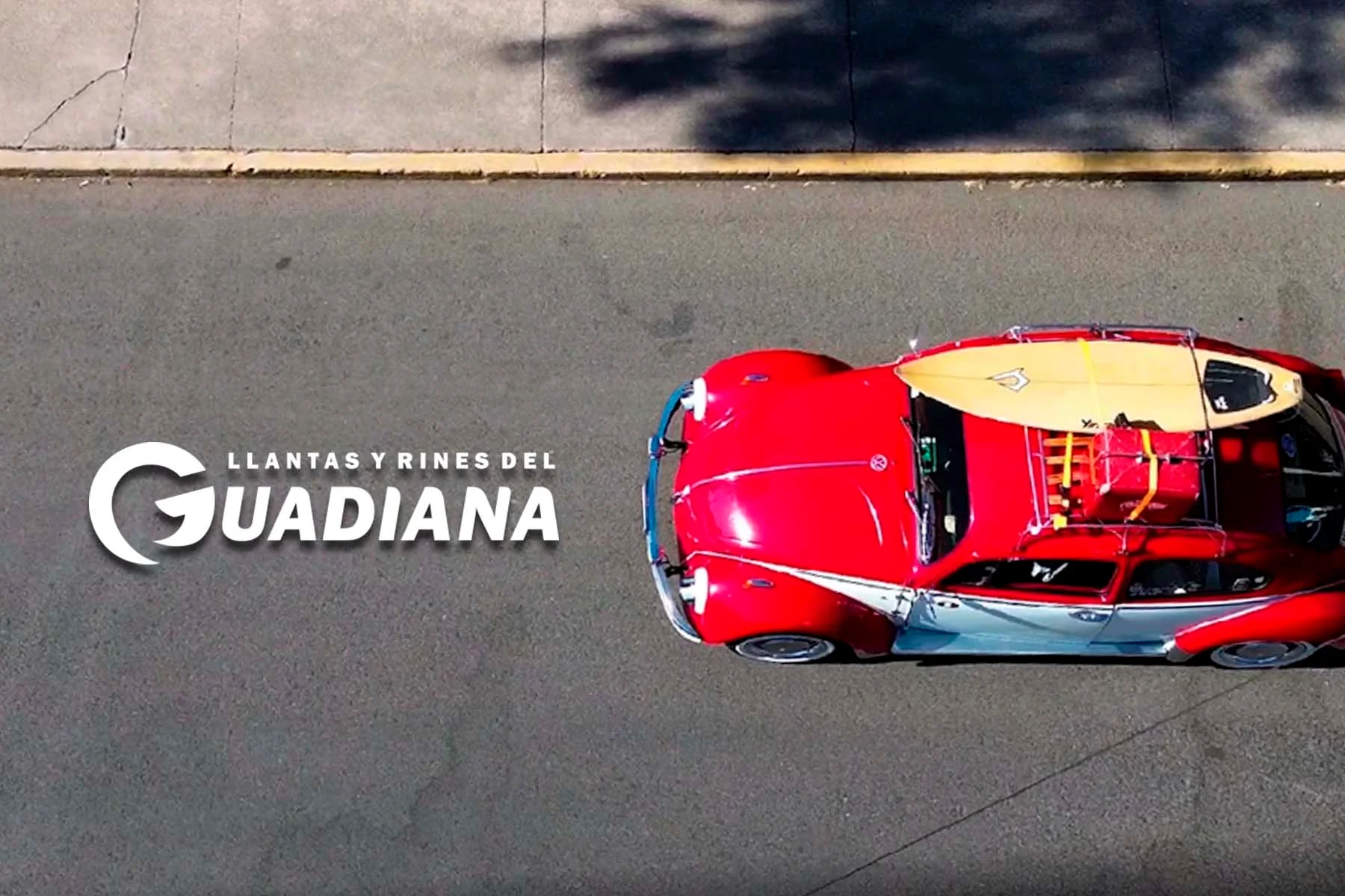 Auto rojo visto desde arriba con logotipo de Llantas y Rines del Guadiana a un costado en la carretera