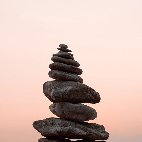 Piedras negras apiladas en fondo rosa claro